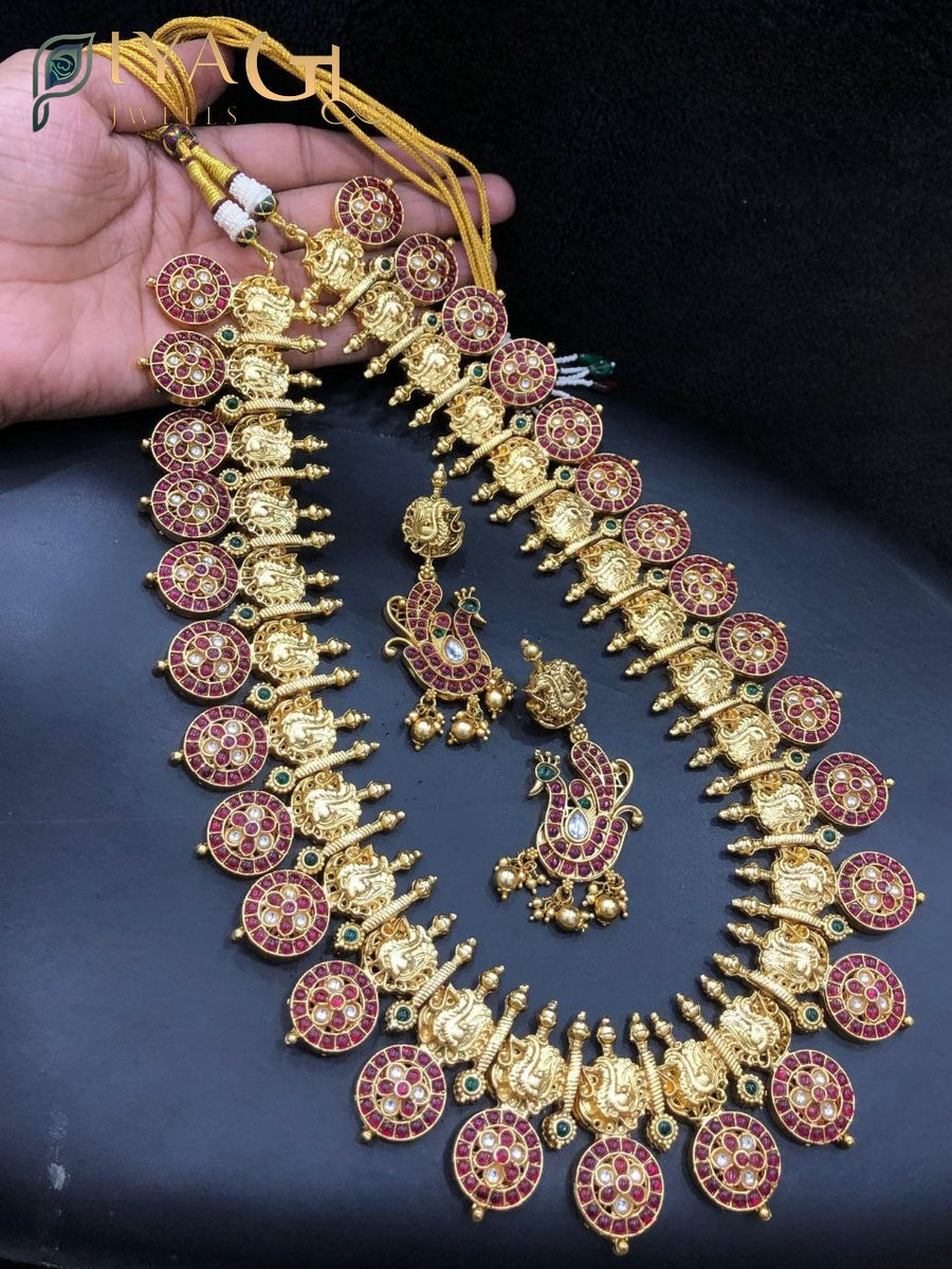 Close up of an antique polish brass metal long haram set with kempu stones, matching earrings and maang tikka displayed on a mannequin. - PiyaGuJwells
