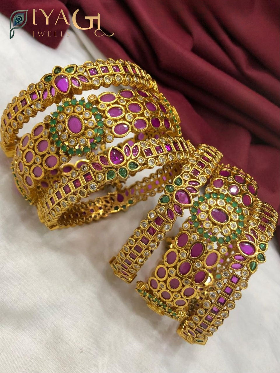 Gold colored imitation bangle kadda set with pink and green stones on white background - PiyaGuJwells
