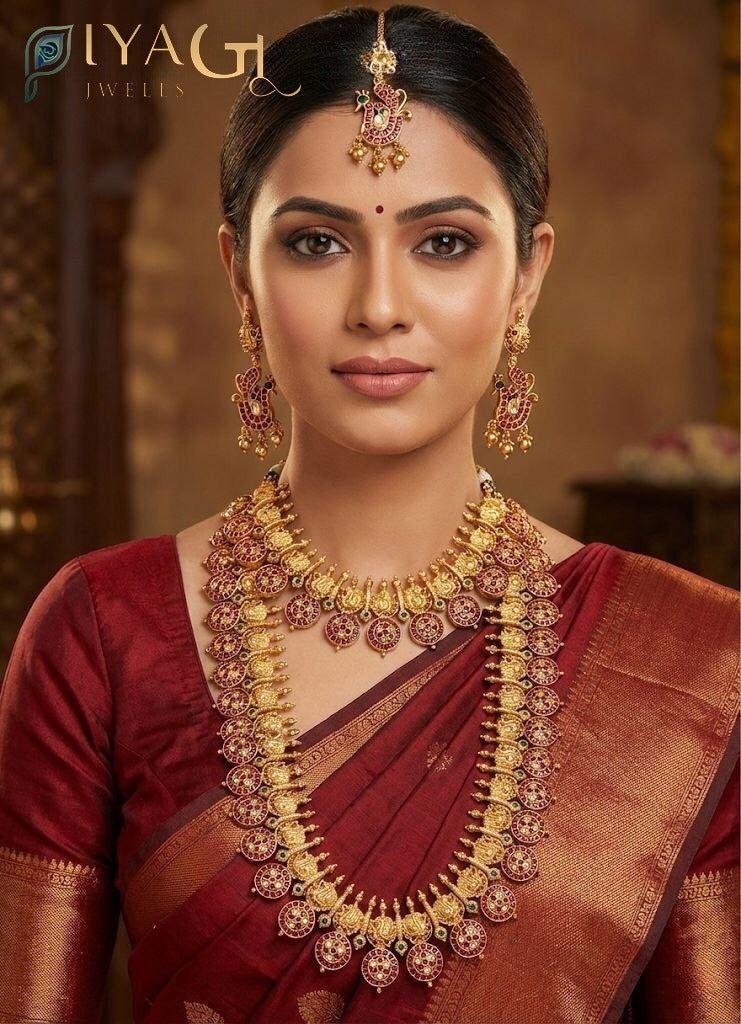 Woman wearing an antique finish brass metal jewelry set with red kempu stones, including a peacock maang tikka, long earrings, and a double-layered necklace. - PiyaGuJwells