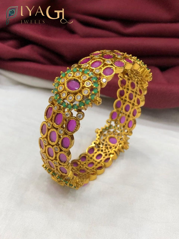 Golden antique finish bangle kada with pink, green and white imitation stones on a white background. - PiyaGuJwells