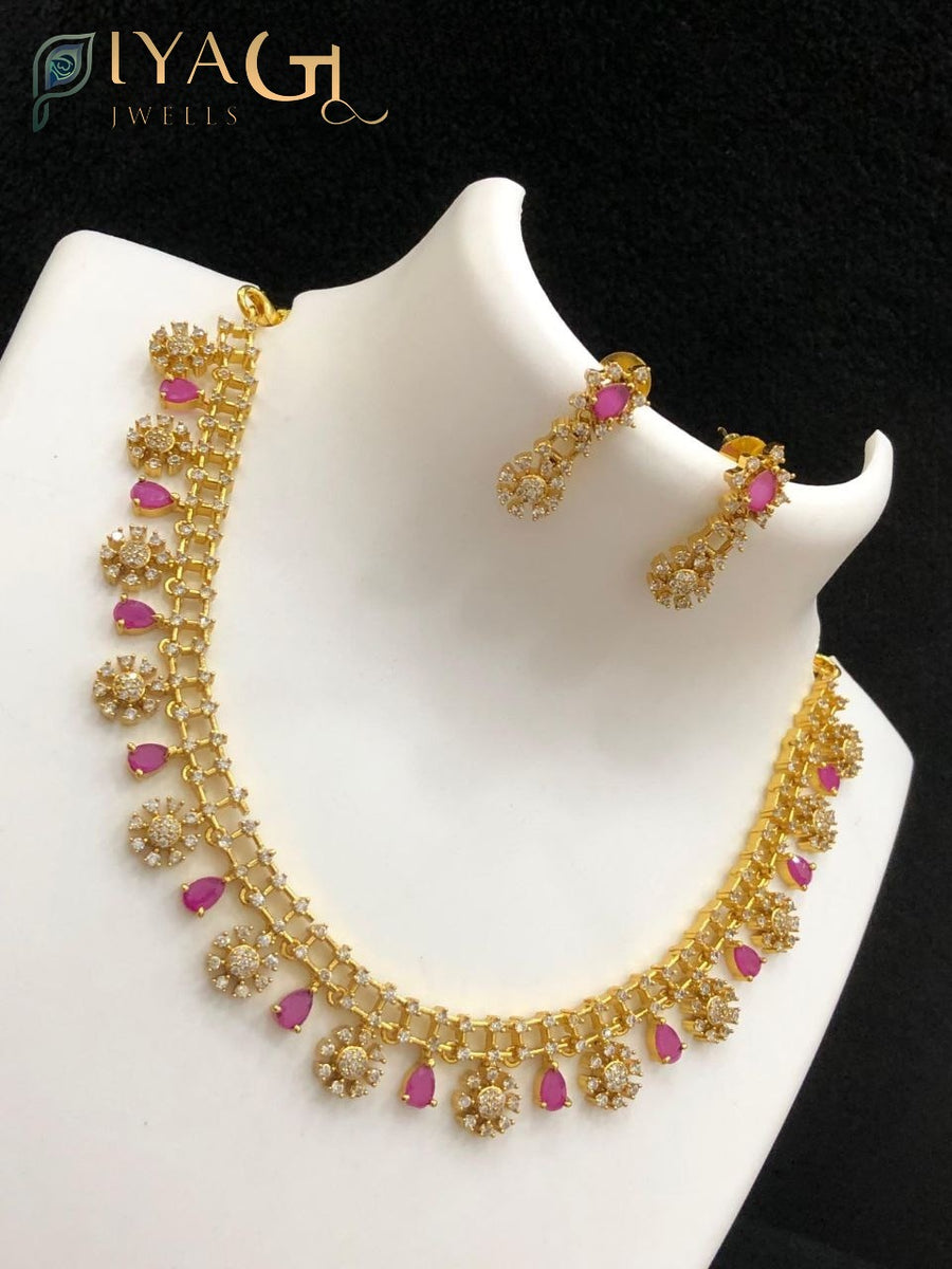 Gold-colored antique finish necklace set with pink and green imitation stones and matching earrings displayed on a bust. - PiyaGuJwells