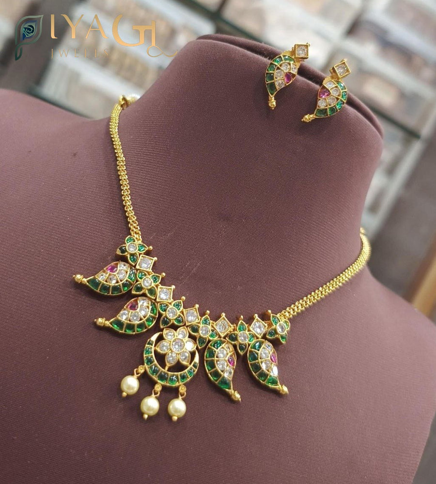 Close up of a gold-tone necklace set with green and white stones on a bust stand. - PiyaGuJwells