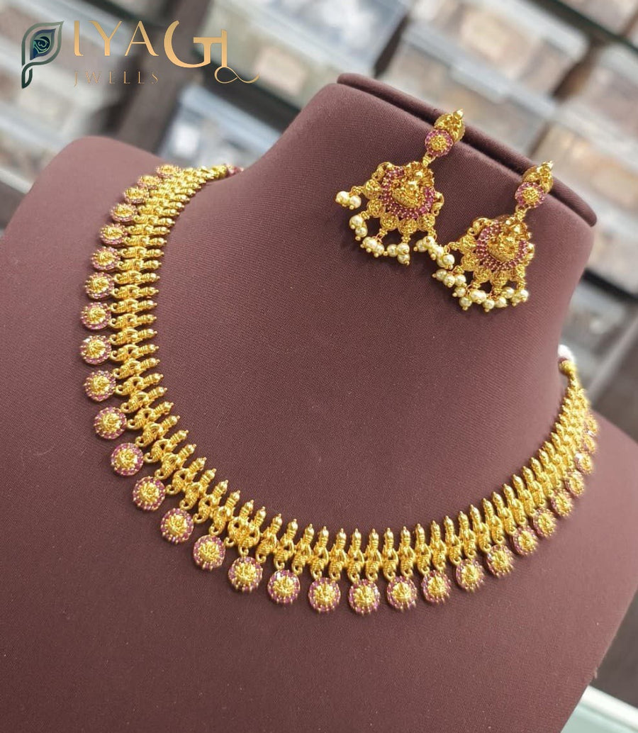 Hand holding antique finish brass jhumka earrings with green stone and intricate Nagas work design. - PiyaGuJwells