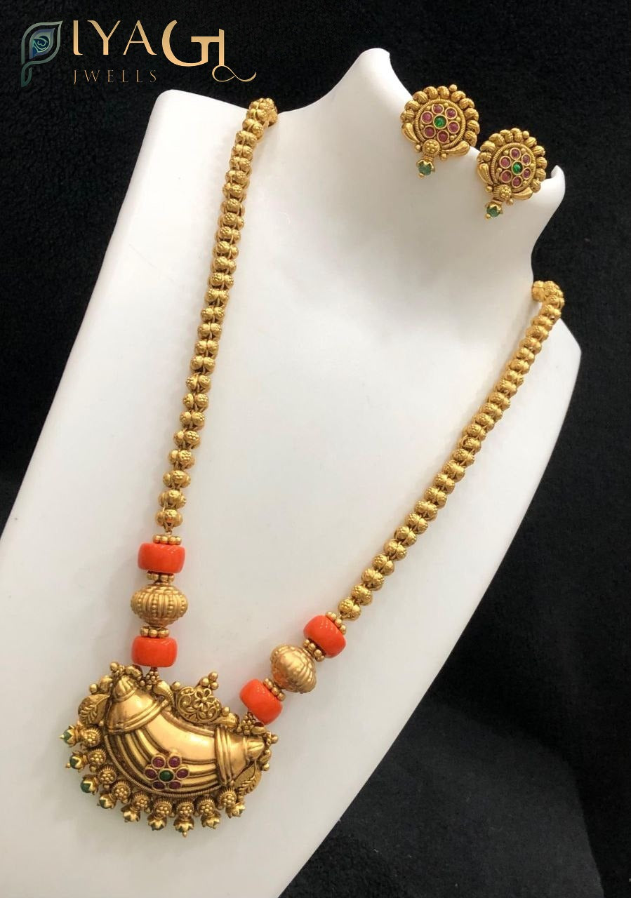 Gold colored brass necklace set with orange coral beads and matching earrings on a white bust - PiyaGuJwells