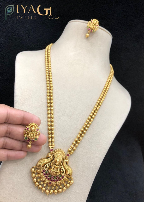 Imitation gold temple jewelry long necklace set with deity pendant and matching earrings featuring red and green stones - PiyaGuJwells