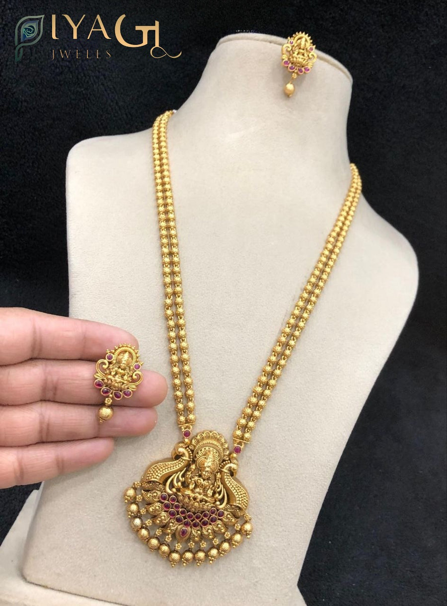 Imitation gold temple jewelry long necklace set with deity pendant and matching earrings featuring red and green stones - PiyaGuJwells