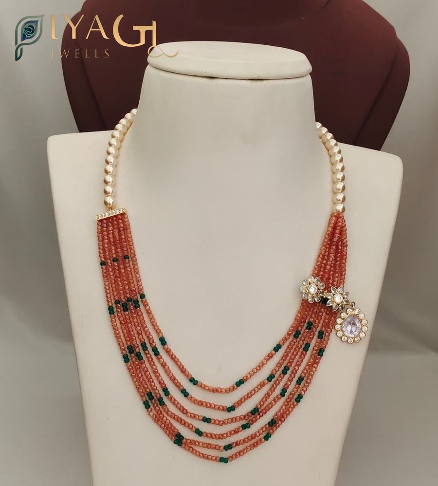 Multi-strand peach beaded necklace with green accents and stone flower pendant displayed on a white bust. - PiyaGuJwells
