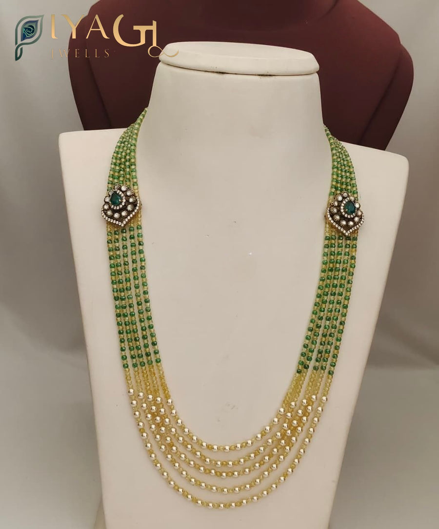 White mannequin displaying a multi-layered green and yellow beaded necklace with floral stone clusters by PC's. - PiyaGuJwells