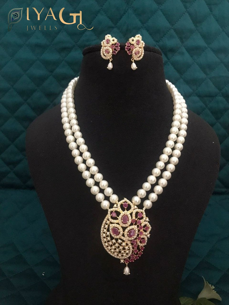 Imitation pearl mala set with matching earrings and pendant in purple, red, and white variations displayed on a black bust. - PiyaGuJwells