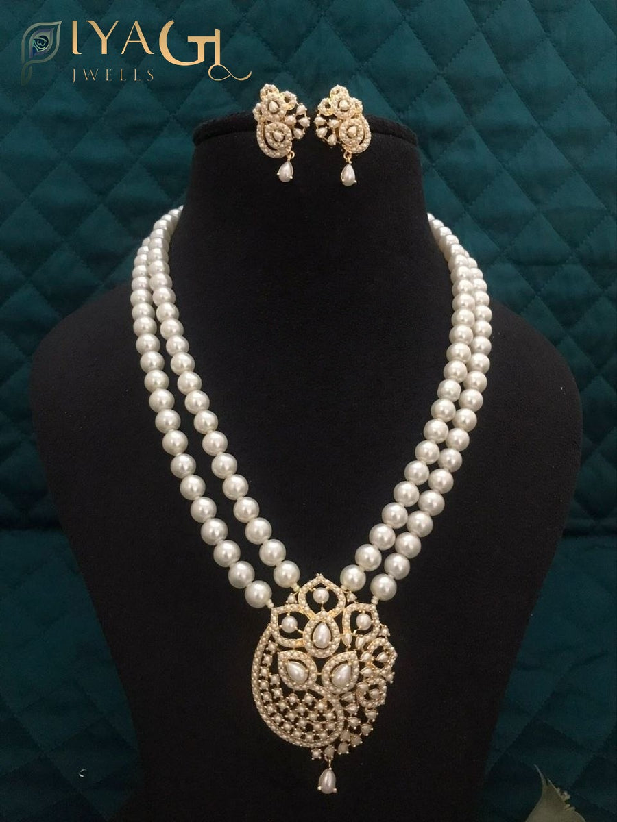 Imitation pearl mala set with matching earrings and pendant in purple, red, and white variations displayed on a black bust. - PiyaGuJwells