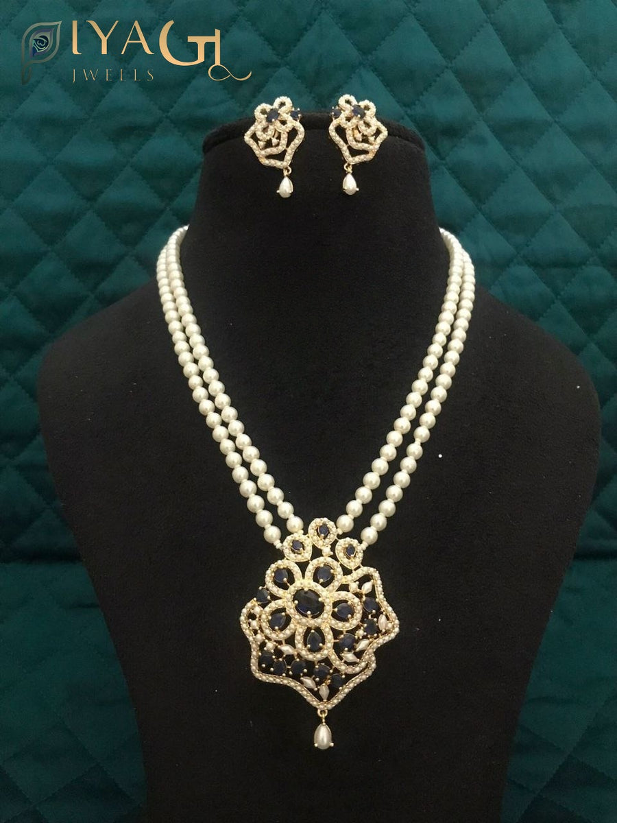 Black mannequin displaying a double strand pearl necklace with a floral pendant and matching earrings. - PiyaGuJwells