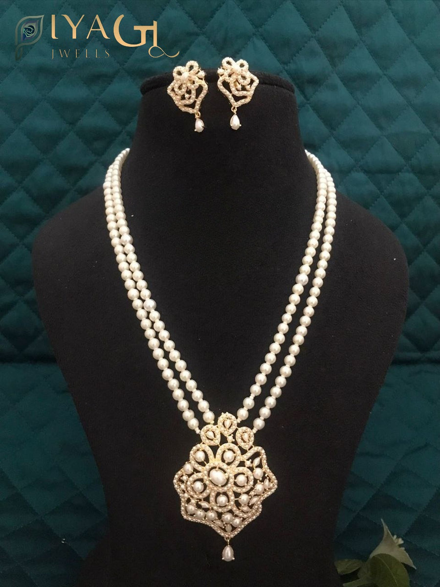 Black mannequin displaying a double strand pearl necklace with a floral pendant and matching earrings. - PiyaGuJwells