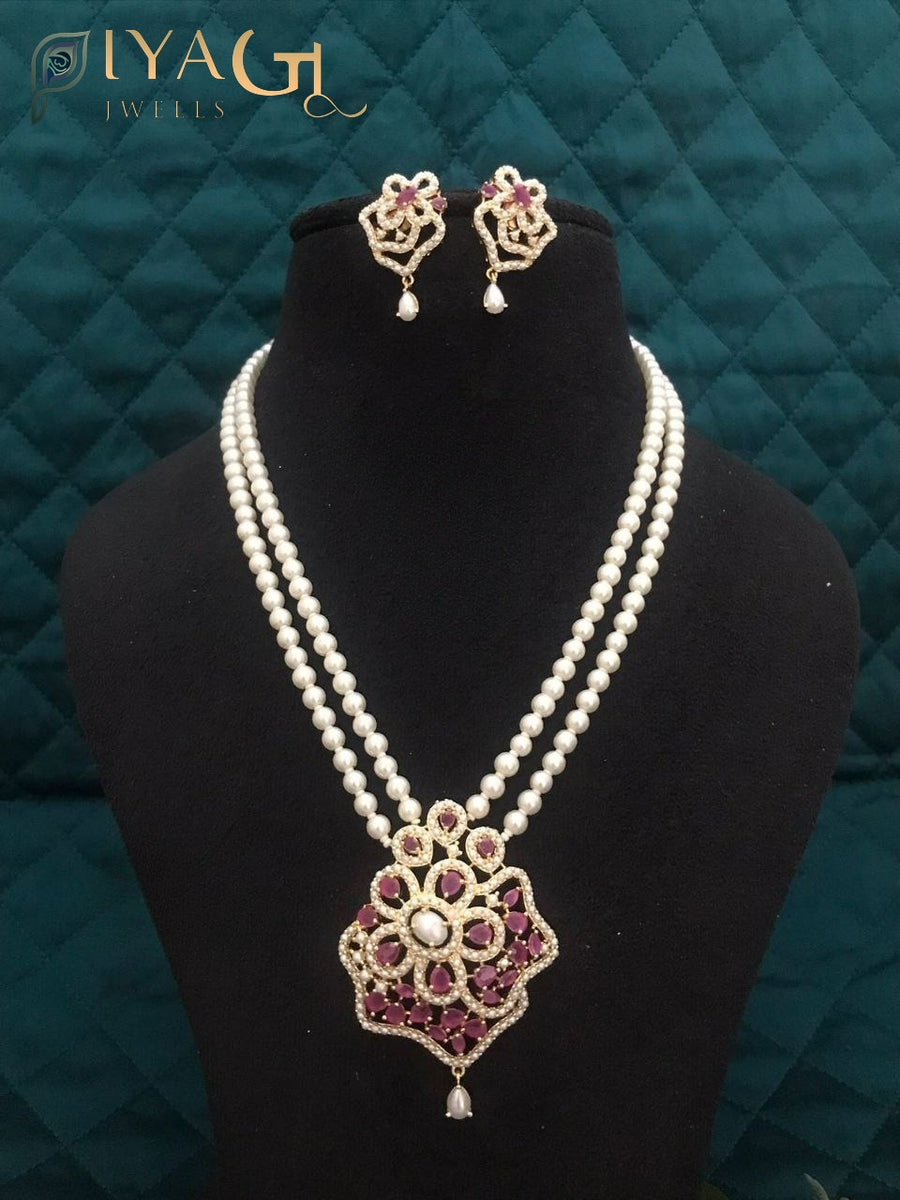 Black mannequin displaying a double strand pearl necklace with a floral pendant and matching earrings. - PiyaGuJwells