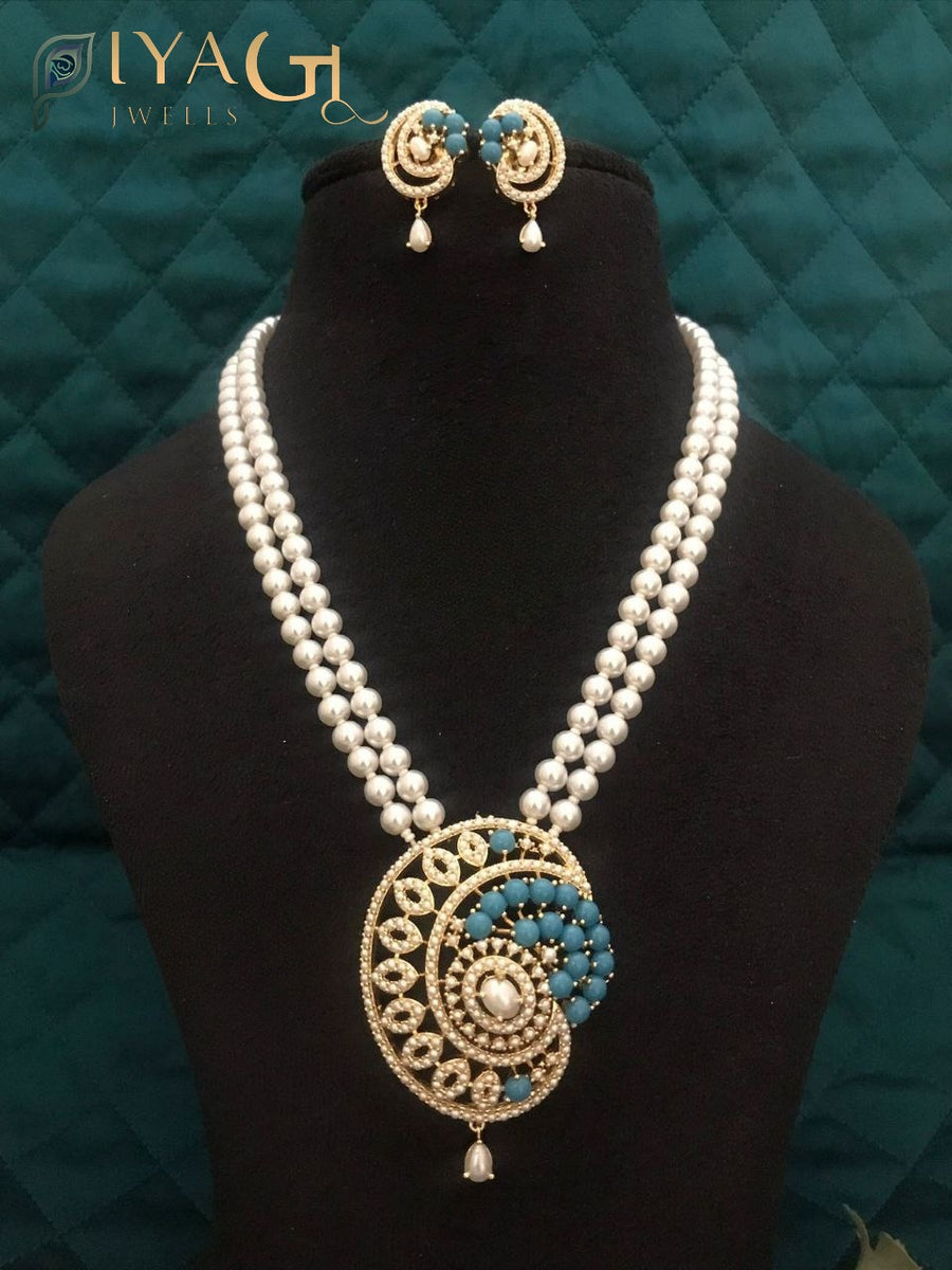 Imitation pearl mala set with large spiral pendant and matching earrings displayed on a black bust against a green background. - PiyaGuJwells